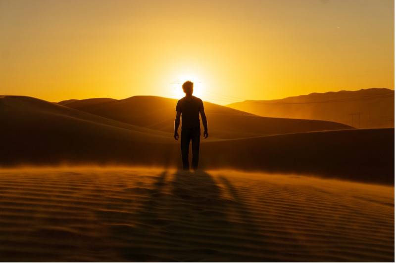 Man standing in a sunny desert in the evening